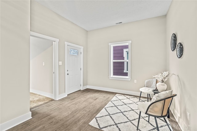 entrance foyer featuring visible vents, a textured ceiling, baseboards, and wood finished floors