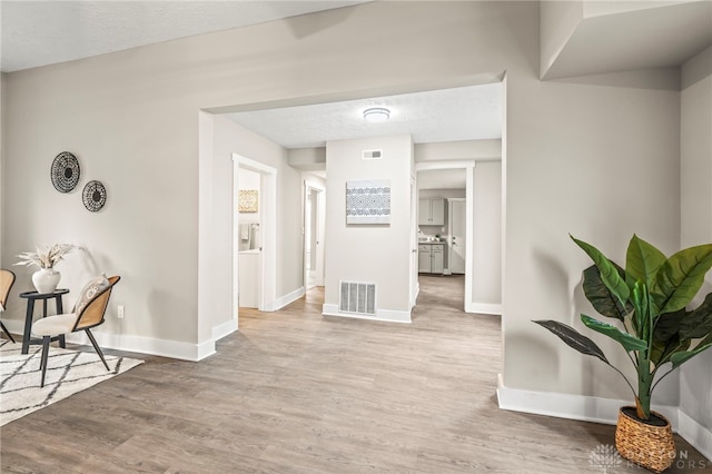 hallway featuring baseboards, visible vents, and wood finished floors