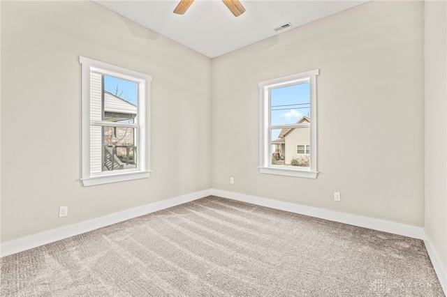 carpeted empty room featuring a wealth of natural light, visible vents, and baseboards