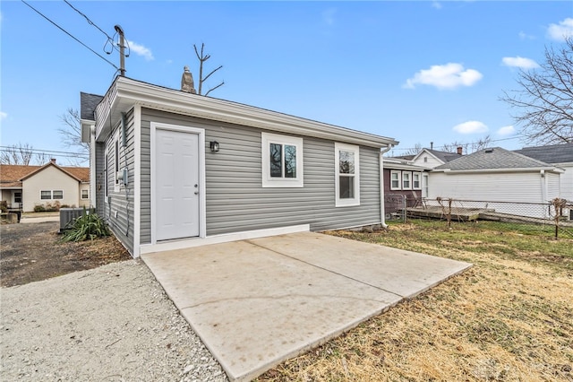 back of property with central AC unit, a lawn, a chimney, fence, and a patio area