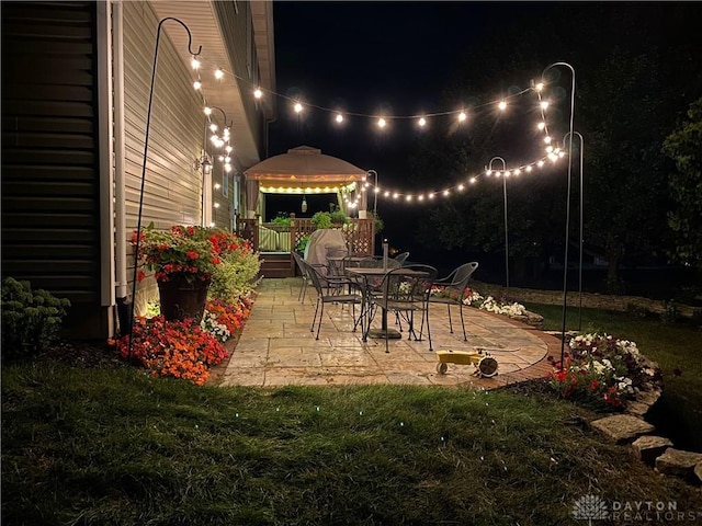 patio at twilight featuring a gazebo and a yard