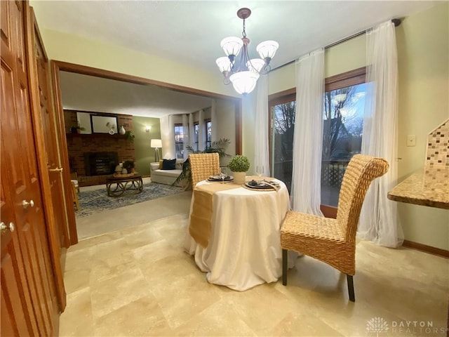 dining room with a brick fireplace and a notable chandelier