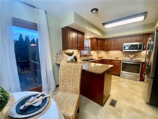 kitchen with tasteful backsplash, stainless steel appliances, kitchen peninsula, and sink