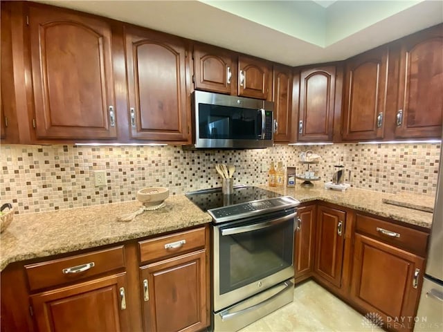 kitchen with stainless steel appliances, backsplash, and light stone counters