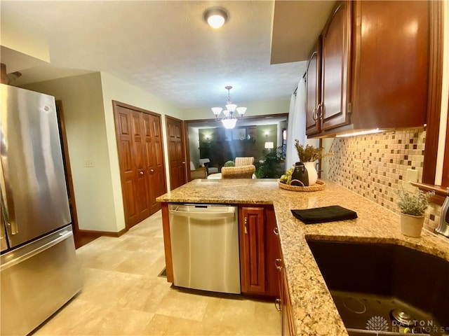 kitchen with sink, hanging light fixtures, stainless steel appliances, light stone counters, and tasteful backsplash