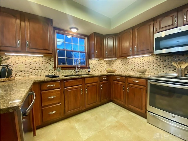 kitchen with light stone counters, sink, tasteful backsplash, and stainless steel appliances