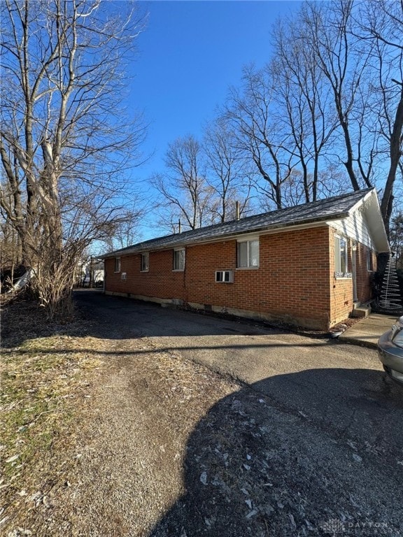 view of property exterior featuring driveway and brick siding