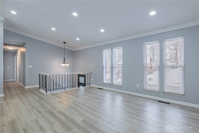 empty room with crown molding, baseboards, wood finished floors, and visible vents