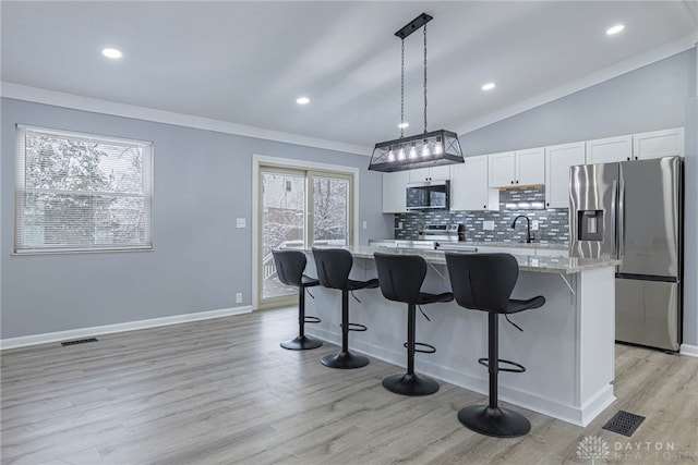 kitchen with visible vents, decorative backsplash, a kitchen breakfast bar, a sink, and stainless steel appliances
