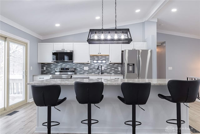 kitchen with stainless steel appliances, decorative backsplash, light wood-style flooring, and lofted ceiling