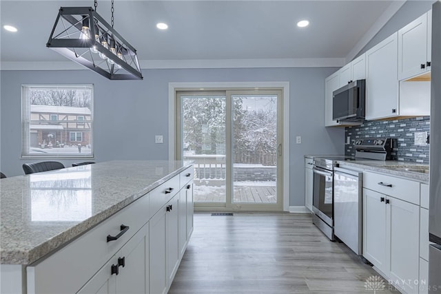 kitchen with white cabinets, appliances with stainless steel finishes, light stone counters, recessed lighting, and tasteful backsplash