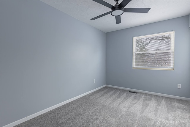 carpeted empty room featuring baseboards, ceiling fan, a textured ceiling, and visible vents