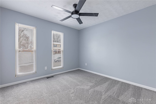 unfurnished room with carpet floors, baseboards, visible vents, and ceiling fan