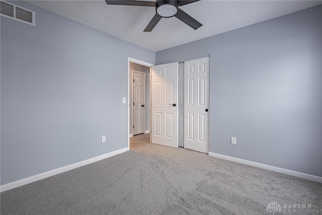 unfurnished bedroom featuring visible vents, a closet, baseboards, ceiling fan, and carpet