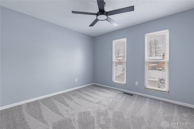 carpeted empty room featuring baseboards, a ceiling fan, and visible vents