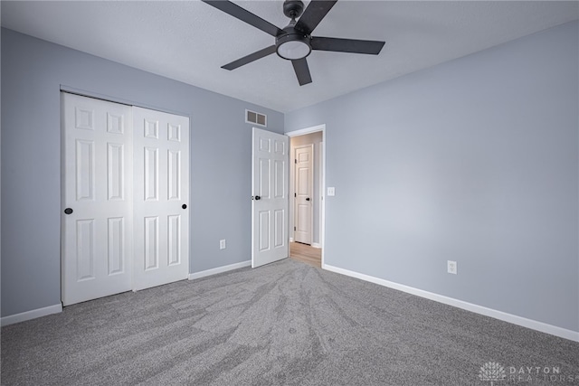 unfurnished bedroom featuring visible vents, carpet floors, a closet, baseboards, and a ceiling fan