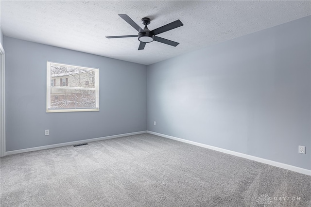 carpeted empty room with baseboards, a textured ceiling, visible vents, and ceiling fan