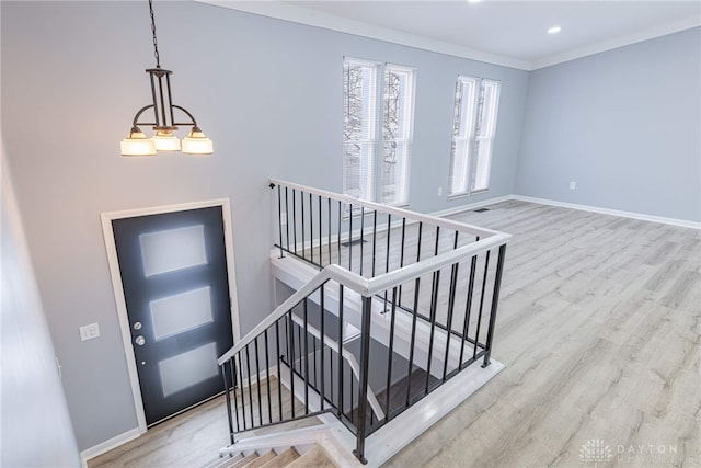 foyer entrance featuring baseboards, ornamental molding, wood finished floors, and stairway