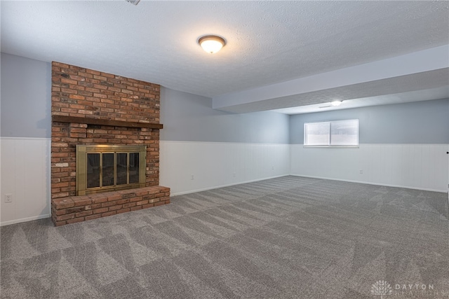 below grade area with carpet floors, a textured ceiling, a fireplace, and a wainscoted wall