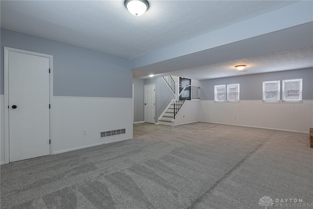 below grade area featuring stairway, carpet floors, wainscoting, and visible vents
