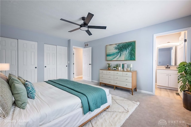 bedroom featuring a sink, ensuite bath, two closets, baseboards, and visible vents