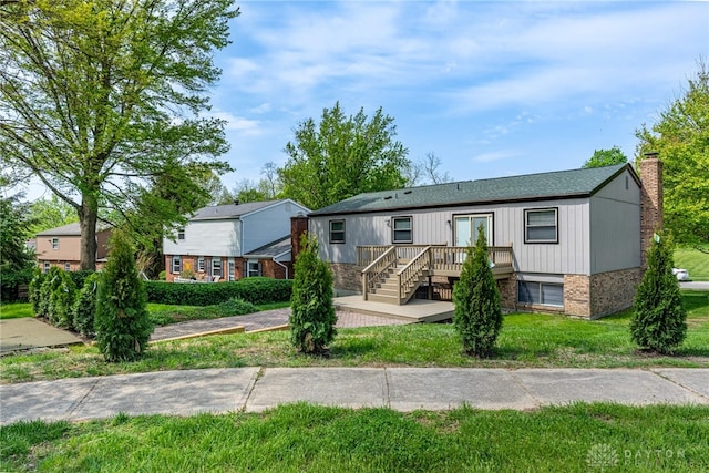 view of front of house featuring roof with shingles, a chimney, brick siding, and a front yard
