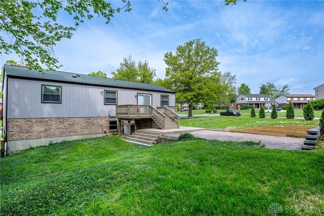 back of property with a yard, brick siding, and a deck