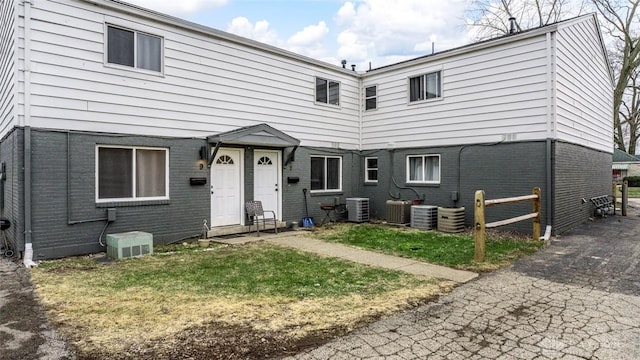 front facade featuring central AC unit and a front yard