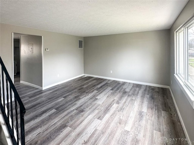 spare room featuring dark wood-type flooring and a textured ceiling