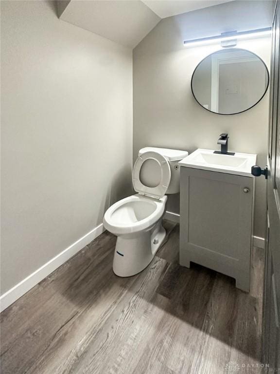 bathroom featuring vanity, vaulted ceiling, hardwood / wood-style floors, and toilet