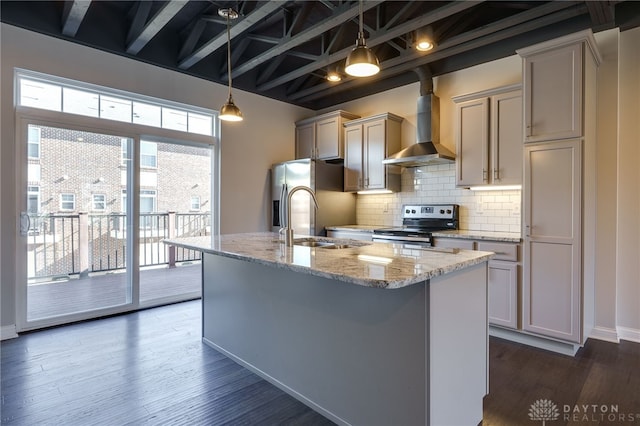 kitchen featuring sink, appliances with stainless steel finishes, wall chimney range hood, light stone countertops, and backsplash