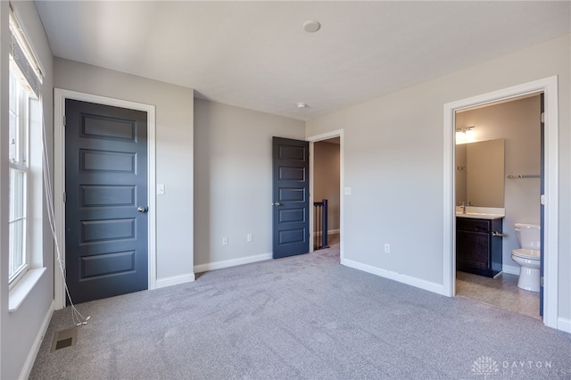 unfurnished bedroom featuring multiple windows, sink, and light carpet