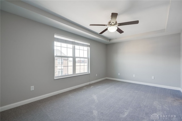 carpeted spare room with ceiling fan and a tray ceiling