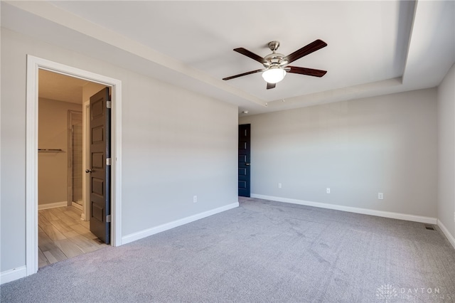 carpeted empty room featuring a tray ceiling and ceiling fan