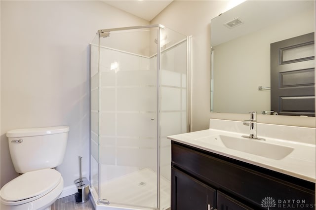 bathroom featuring vanity, a shower with shower door, and toilet