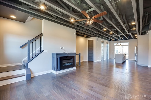 unfurnished living room with dark hardwood / wood-style flooring, sink, and ceiling fan