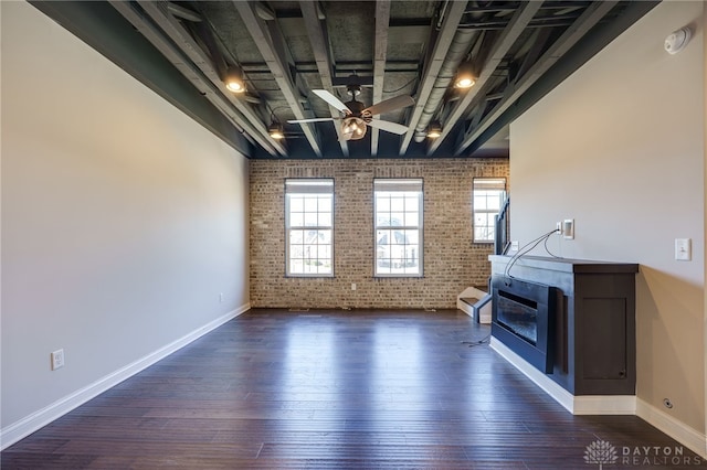 unfurnished living room featuring dark hardwood / wood-style flooring, a fireplace, ceiling fan, and brick wall