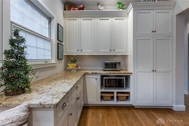 kitchen featuring white cabinetry, light stone counters, and light hardwood / wood-style floors