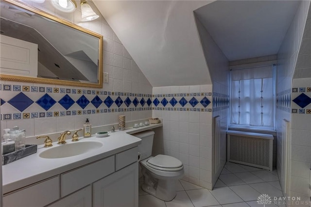 bathroom featuring toilet, vaulted ceiling, tile walls, radiator heating unit, and tile patterned flooring