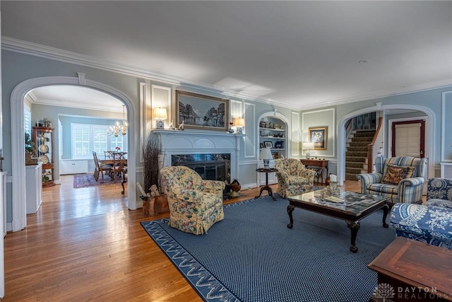 living room featuring hardwood / wood-style flooring, a premium fireplace, built in features, and crown molding