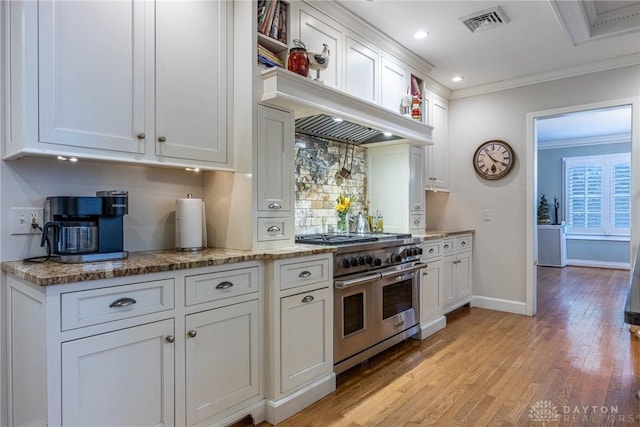 kitchen featuring range with two ovens, ornamental molding, white cabinets, and light hardwood / wood-style flooring