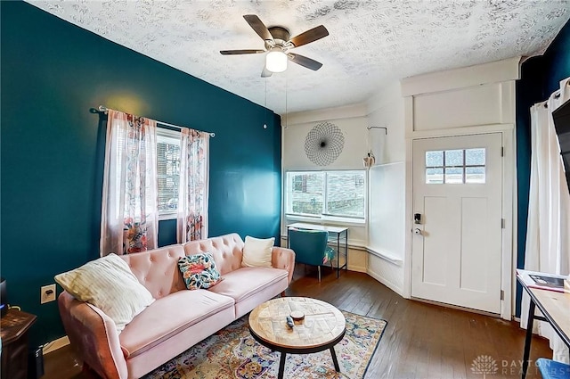 living room with dark wood-type flooring, a textured ceiling, and ceiling fan