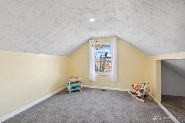 additional living space with visible vents, baseboards, vaulted ceiling, a textured ceiling, and carpet floors