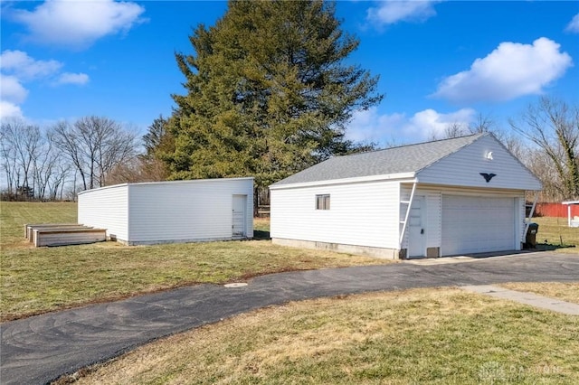 view of side of property featuring a garage, a yard, and an outdoor structure