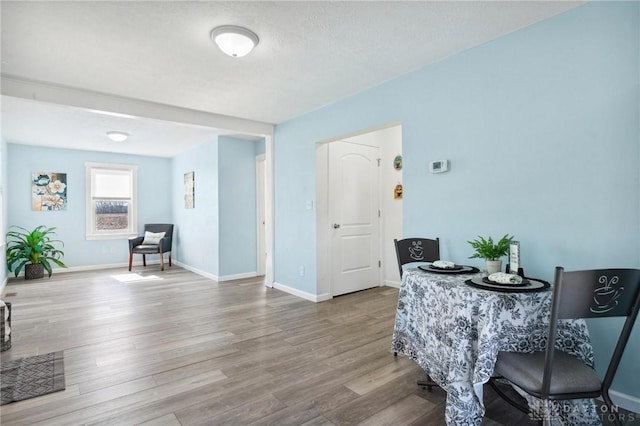 dining space featuring a textured ceiling, baseboards, and wood finished floors