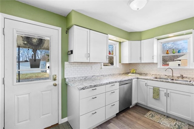 kitchen with dishwasher, tasteful backsplash, a sink, and white cabinets