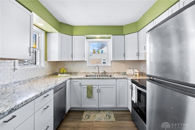 kitchen featuring white cabinets, appliances with stainless steel finishes, decorative backsplash, and a sink