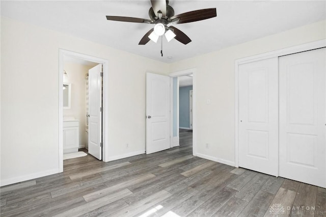 unfurnished bedroom featuring a closet, wood finished floors, connected bathroom, and baseboards