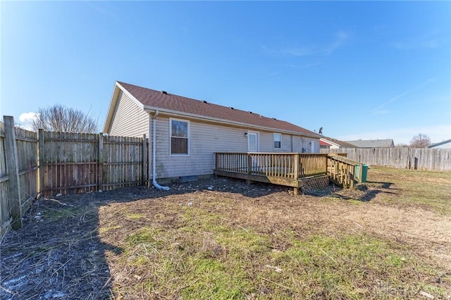 rear view of house featuring a wooden deck and a lawn