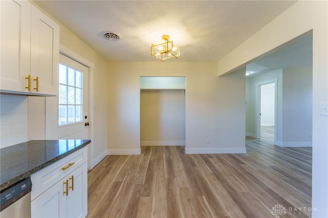 unfurnished dining area featuring light hardwood / wood-style floors and a chandelier